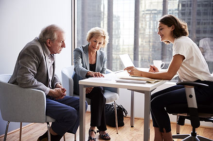 A retirement-age couple speaking in an office with a financial advisor.